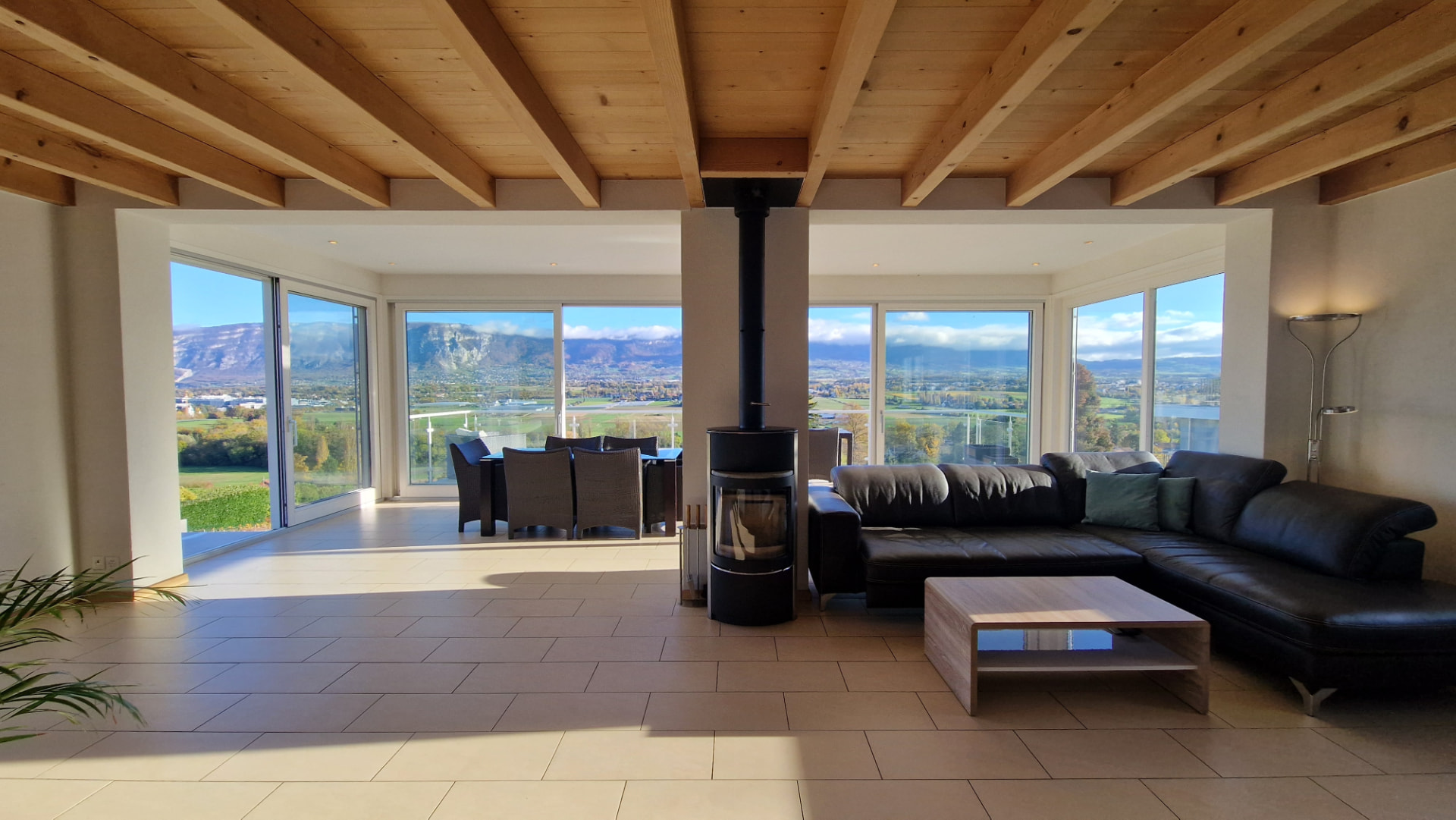 Bright living room with wooden beams and views of the lake and Alps